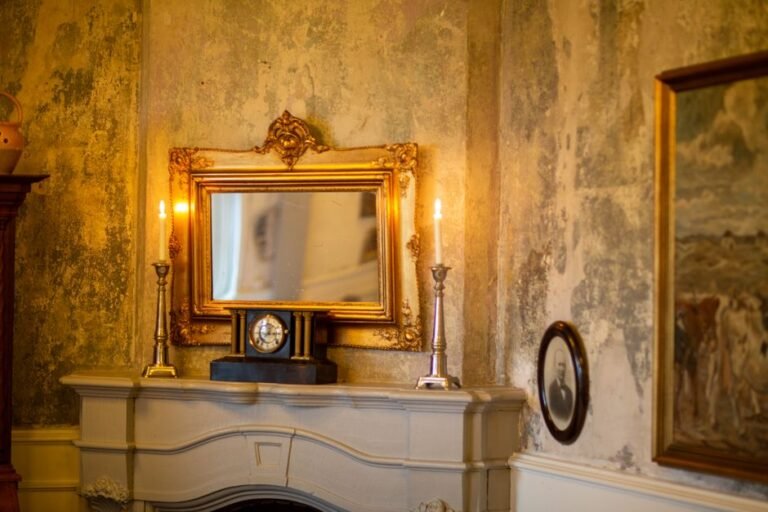 Espejo gótico dorado ornamentado sobre repisa de chimenea con velas encendidas